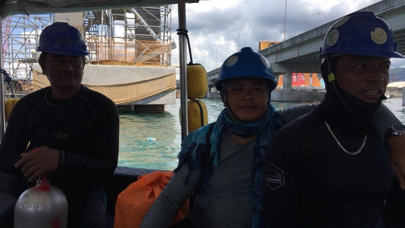 Three Oceantech divers on a boat wearing blue helmets during bridge construction work